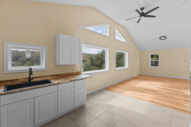 kitchen featuring lofted ceiling, sink, wooden counters, white cabinetry, and light wood-type flooring