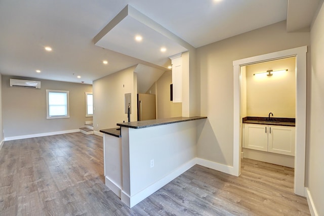 kitchen featuring high quality fridge, white cabinets, a wall mounted AC, and sink