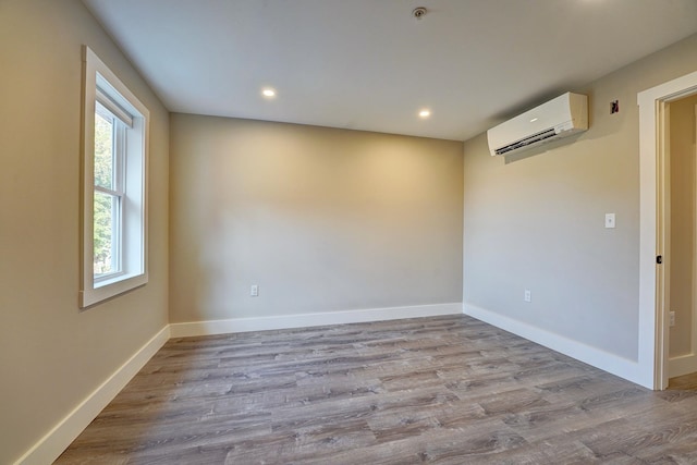 spare room with light wood-type flooring and a wall mounted air conditioner