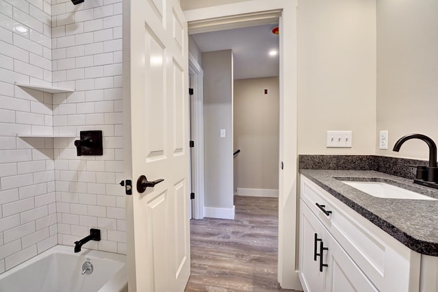 bathroom featuring hardwood / wood-style flooring, tiled shower / bath, and vanity