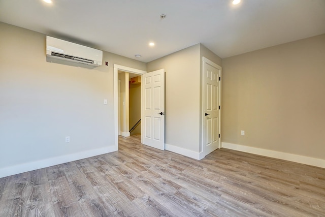 empty room with a wall unit AC and light hardwood / wood-style floors