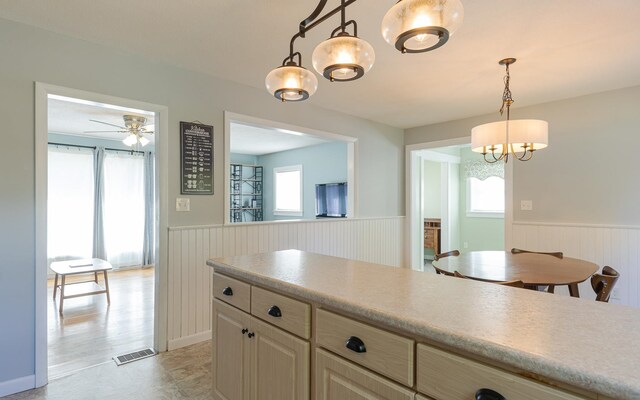 kitchen with pendant lighting, ceiling fan with notable chandelier, plenty of natural light, and light wood-type flooring