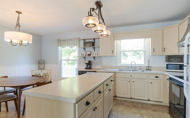 kitchen with black range with electric cooktop, a kitchen island, sink, and decorative light fixtures