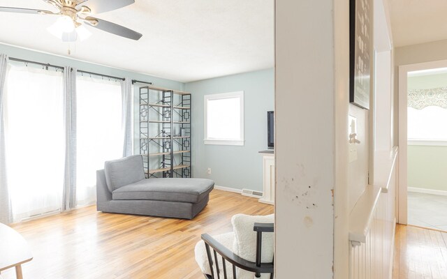 living area featuring light wood-type flooring and ceiling fan