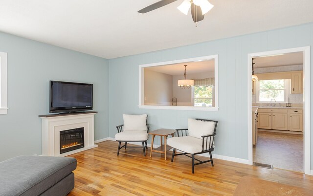 living area featuring ceiling fan, light hardwood / wood-style flooring, sink, and plenty of natural light