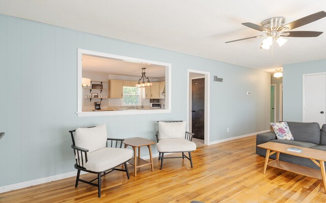 living area with light wood-type flooring, ceiling fan, and sink