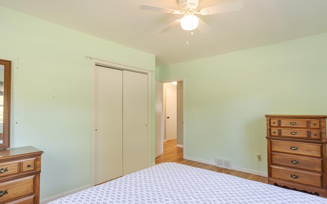 bedroom with ceiling fan, light wood-type flooring, and a closet