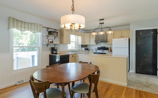 kitchen with decorative backsplash, a kitchen island, light wood-type flooring, black appliances, and decorative light fixtures