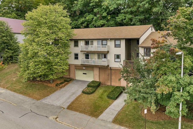 view of property with a garage, a balcony, and driveway