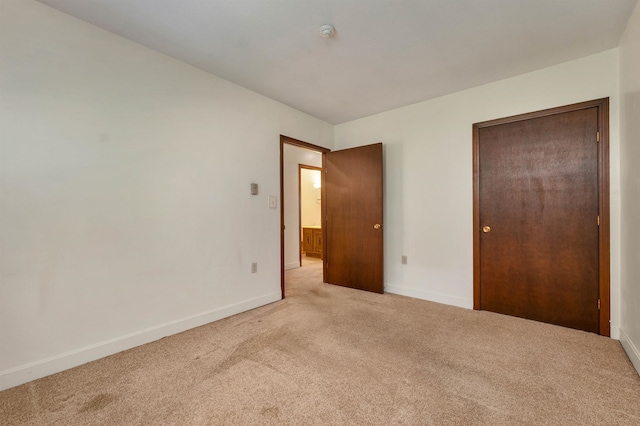 unfurnished bedroom featuring a closet and light colored carpet