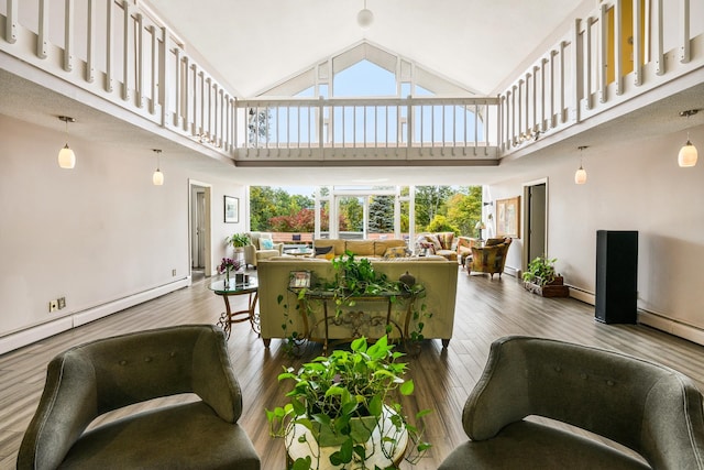 living room featuring high vaulted ceiling, wood-type flooring, a baseboard heating unit, and plenty of natural light