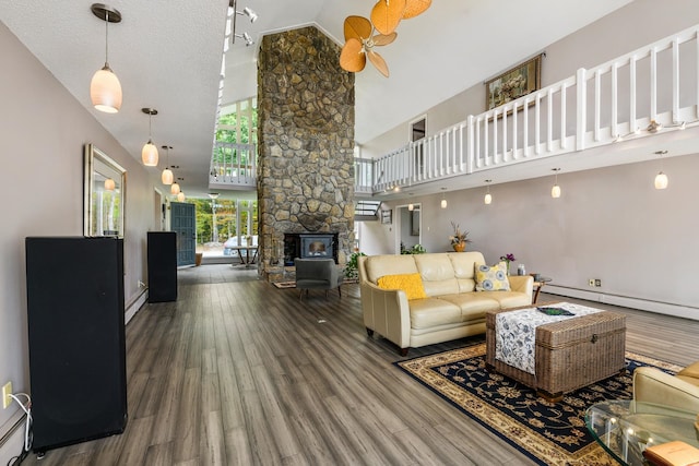 living room featuring a textured ceiling, hardwood / wood-style floors, a wood stove, and high vaulted ceiling