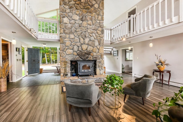 living room with a baseboard radiator, a high ceiling, a wood stove, and dark hardwood / wood-style floors