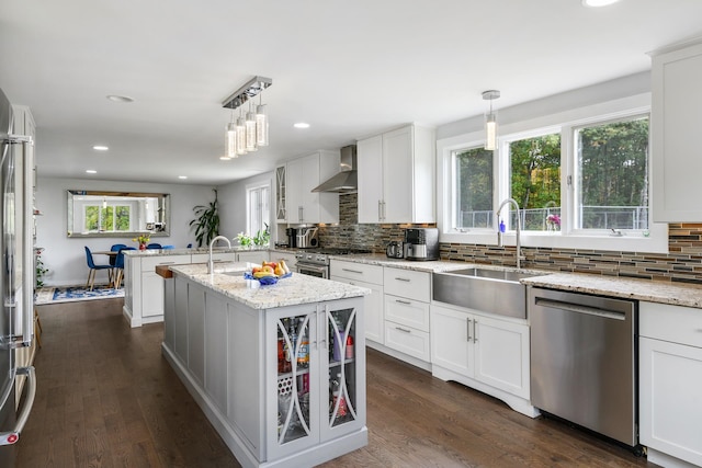 kitchen with decorative light fixtures, a center island with sink, stainless steel appliances, and sink