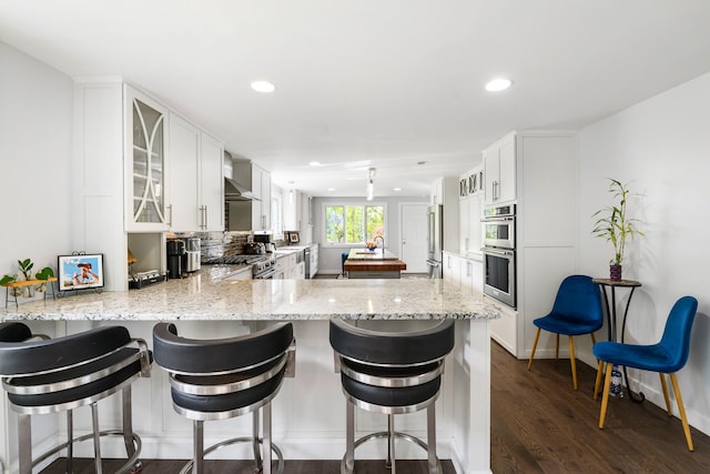 kitchen with white cabinets, a kitchen breakfast bar, dark wood-type flooring, and kitchen peninsula