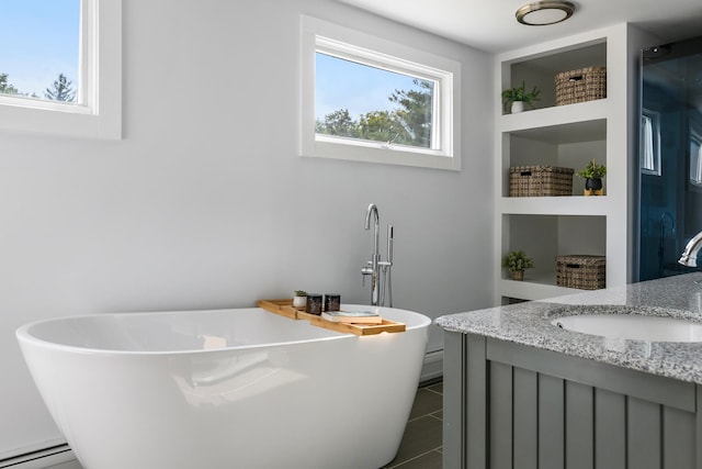 bathroom with a healthy amount of sunlight, tile patterned floors, vanity, and a bathing tub