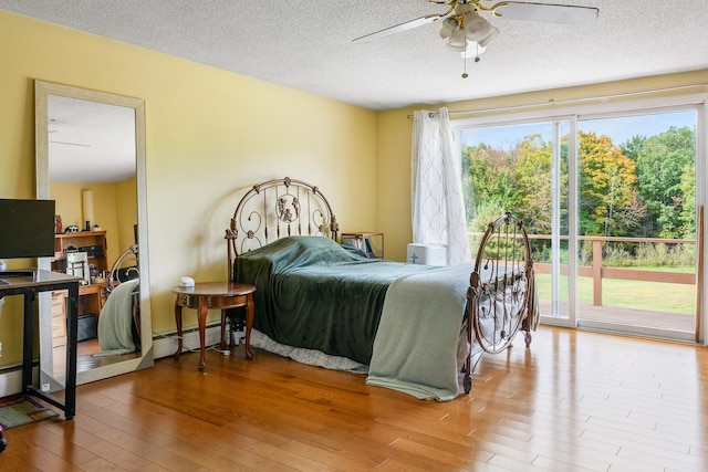 bedroom featuring a textured ceiling, access to exterior, a baseboard radiator, hardwood / wood-style floors, and ceiling fan