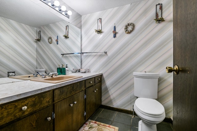 bathroom with a textured ceiling, vanity, toilet, and tile patterned floors