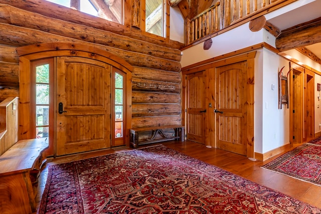 entrance foyer with high vaulted ceiling, beamed ceiling, dark hardwood / wood-style floors, and log walls