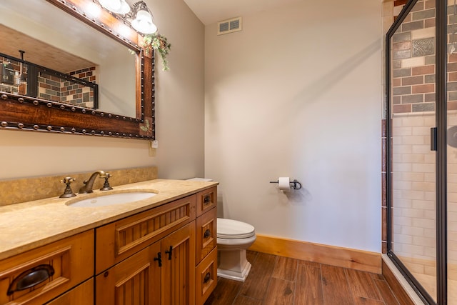 bathroom with walk in shower, vanity, hardwood / wood-style floors, and toilet