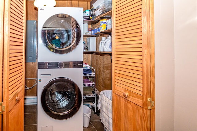 clothes washing area featuring stacked washer / dryer and dark tile patterned floors