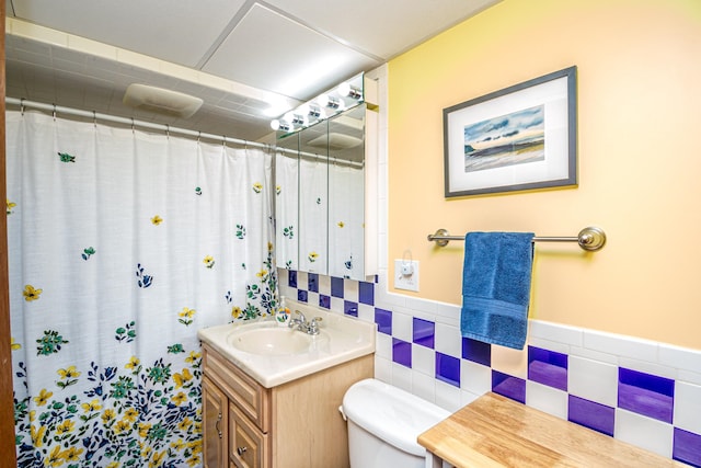 bathroom featuring tile walls, walk in shower, vanity, and toilet