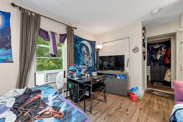 bedroom featuring a textured ceiling, wood-type flooring, and cooling unit