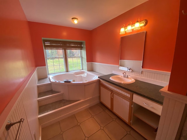bathroom with a jetted tub, wainscoting, tile patterned floors, and vanity