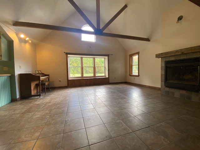 unfurnished living room with a healthy amount of sunlight, high vaulted ceiling, beamed ceiling, and ceiling fan