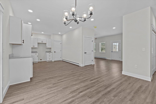 unfurnished living room featuring an inviting chandelier, light hardwood / wood-style floors, and a baseboard radiator