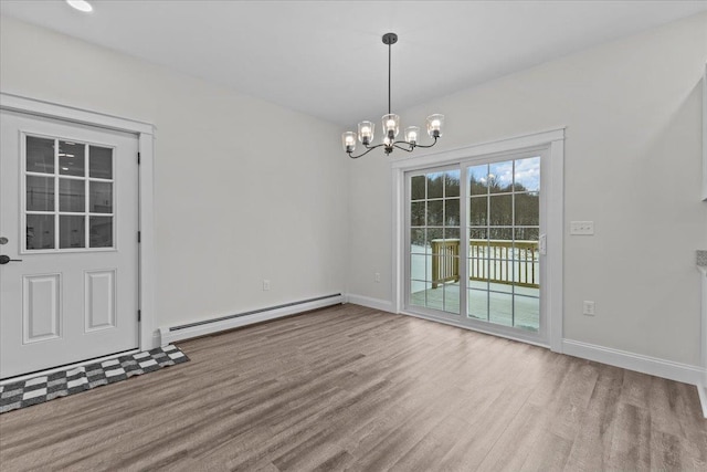 unfurnished dining area featuring hardwood / wood-style flooring, a baseboard heating unit, and a notable chandelier