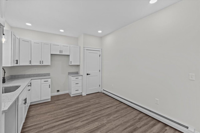 kitchen featuring a baseboard radiator, white cabinetry, and light stone counters