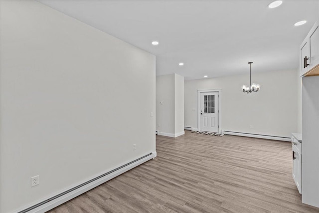 spare room featuring a chandelier, a baseboard radiator, and light hardwood / wood-style floors