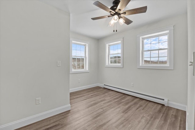 empty room with plenty of natural light, baseboard heating, and ceiling fan