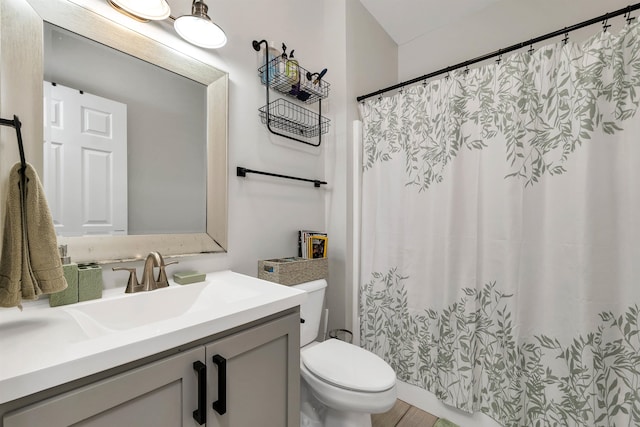 bathroom featuring wood-type flooring, walk in shower, vanity, and toilet