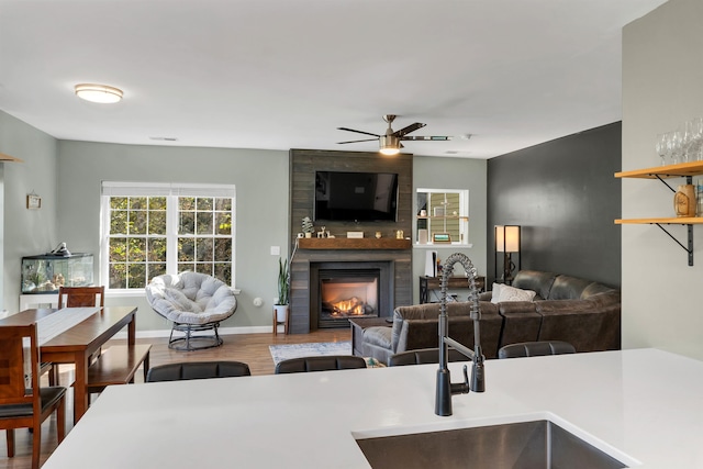 kitchen featuring ceiling fan, hardwood / wood-style flooring, a fireplace, and sink