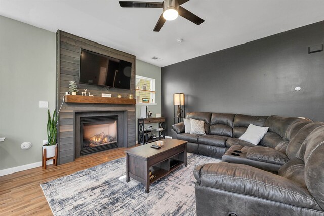 living room featuring light hardwood / wood-style flooring, ceiling fan, and a fireplace