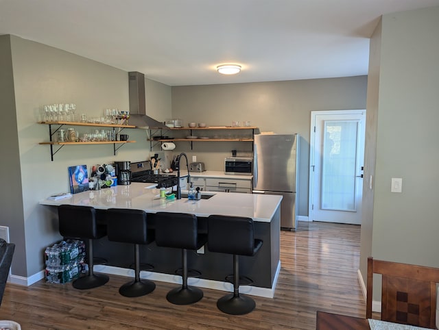 kitchen with a kitchen breakfast bar, wall chimney exhaust hood, kitchen peninsula, and stainless steel appliances