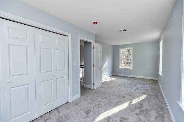 unfurnished bedroom with a closet and light colored carpet