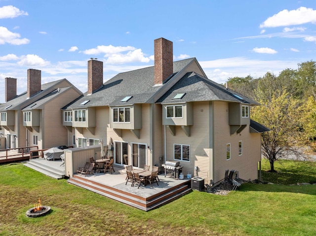 rear view of house with a yard, a deck, and a fire pit