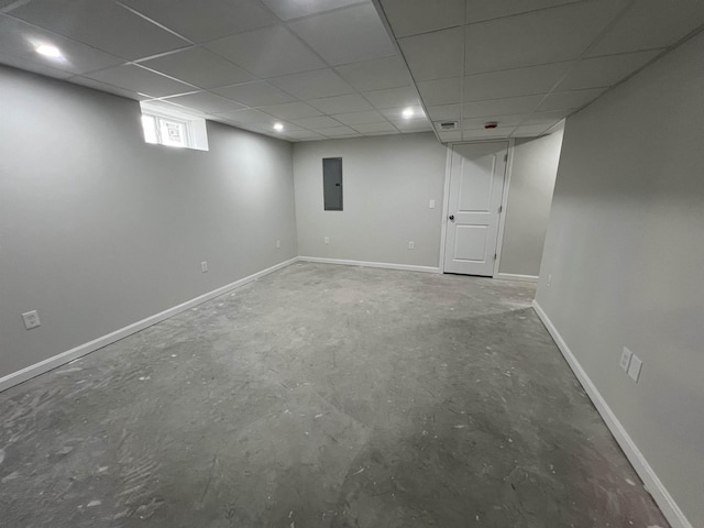 basement featuring a drop ceiling and electric panel