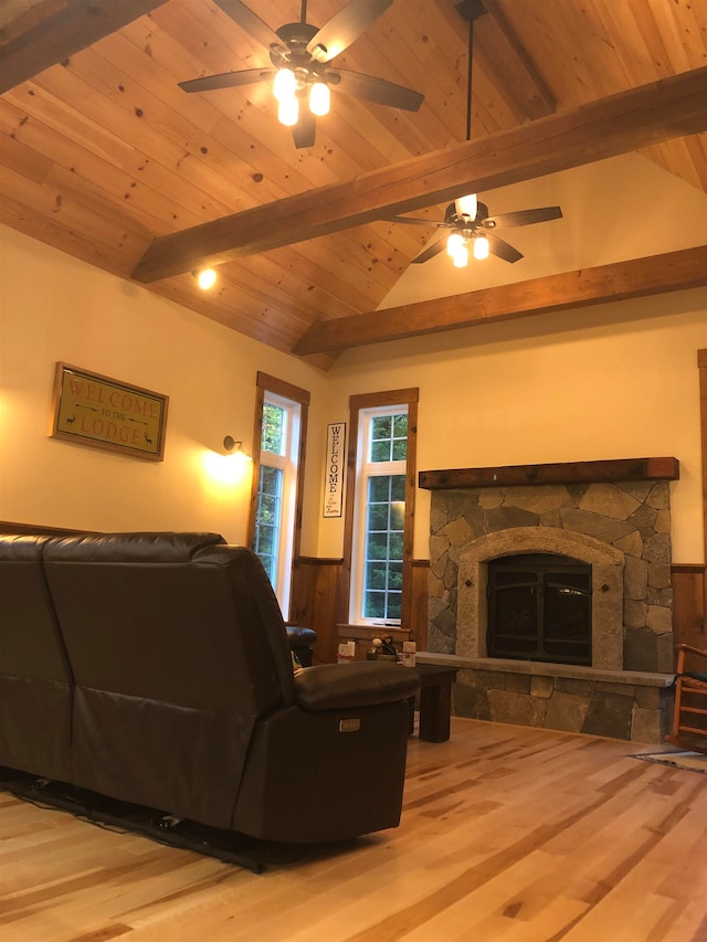 living room featuring hardwood / wood-style floors, lofted ceiling with beams, a stone fireplace, and wood ceiling