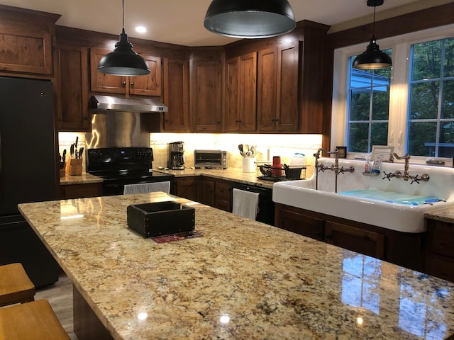 kitchen featuring decorative light fixtures, light stone counters, tasteful backsplash, and black appliances