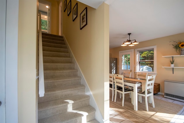 stairs featuring hardwood / wood-style flooring, heating unit, and a notable chandelier