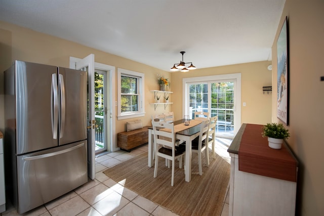 dining space featuring a healthy amount of sunlight, light tile patterned flooring, and an inviting chandelier