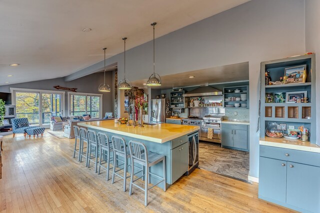 kitchen featuring appliances with stainless steel finishes, pendant lighting, light hardwood / wood-style flooring, a center island, and lofted ceiling