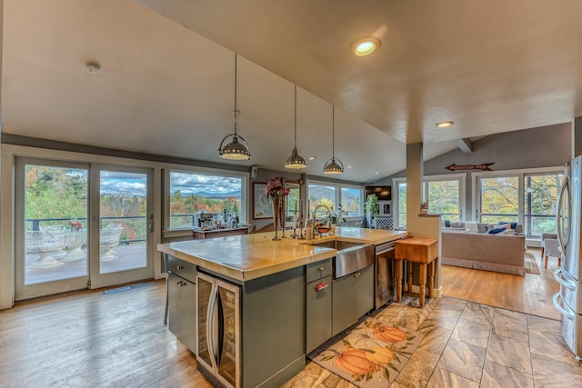 kitchen with a center island with sink, plenty of natural light, pendant lighting, and lofted ceiling