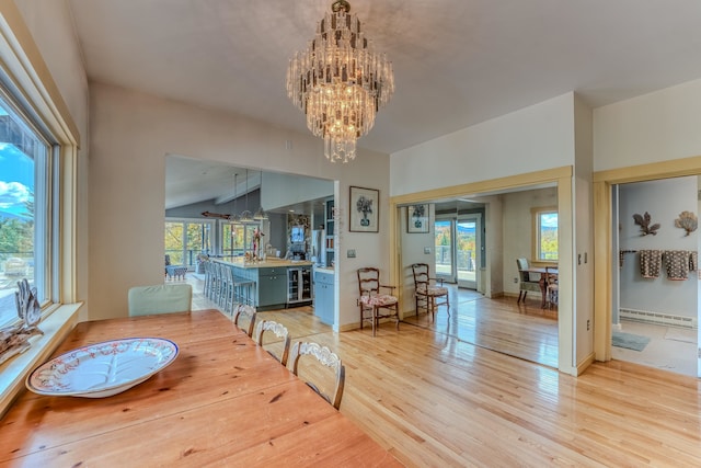 dining space featuring lofted ceiling, an inviting chandelier, light wood-type flooring, baseboard heating, and beverage cooler