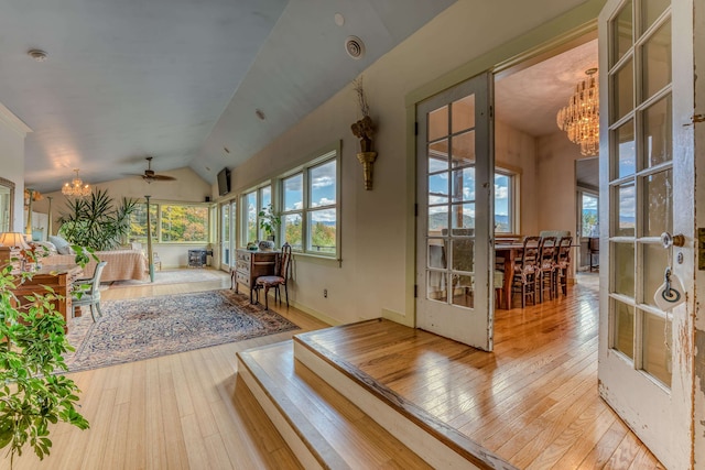 interior space with vaulted ceiling, french doors, and ceiling fan with notable chandelier