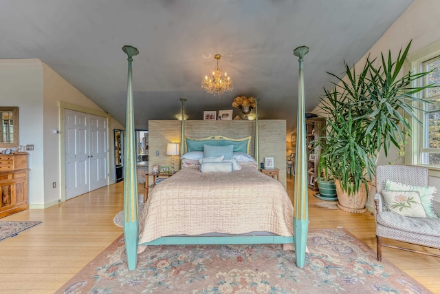 bedroom with an inviting chandelier, vaulted ceiling, and hardwood / wood-style flooring